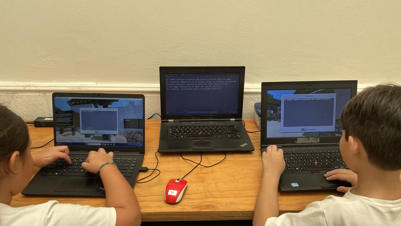 Chicos escribiendo una consigna narrativa a partir de lo construido en Minecraft Education